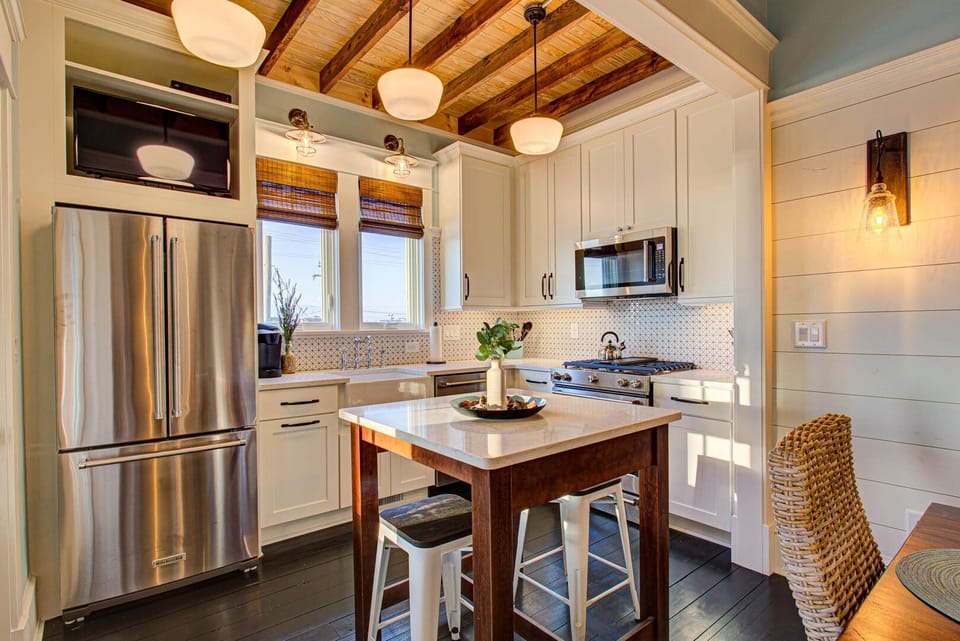 The modern kitchen features stainless steel appliances, a fully stocked prep area, and an island bar with seating for casual meals.