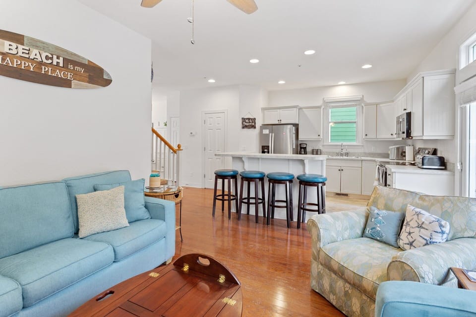 Bottom-Level Living Area: Cozy coastal living room with a smart TV, sleeper sofa, loveseat, and chair for relaxing with family or friends.