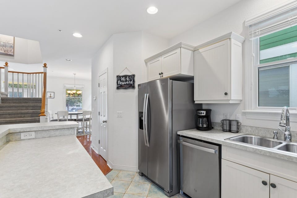 Bottom-Level Kitchen: Fully stocked kitchen with white cabinets, modern appliances, and ample counter space for preparing OBX favorites.