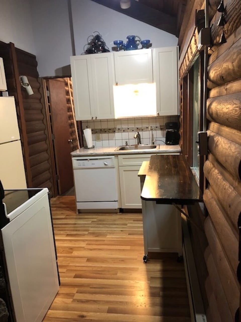 View from front hallway to kitchen dishwasher, sink, work counter and cabinets.
