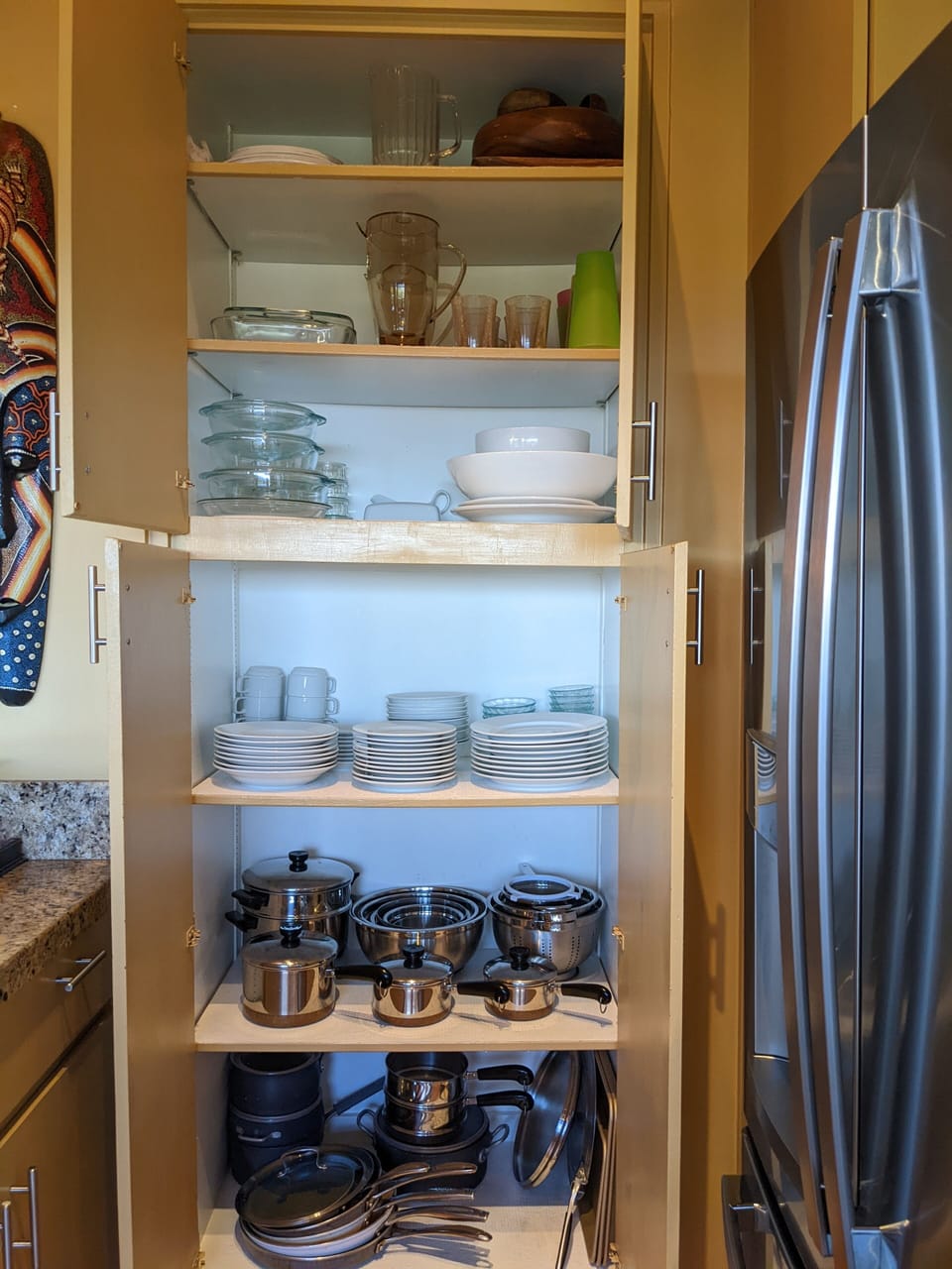 Fully stocked kitchen with cook ware, dishes, and serving utensils.