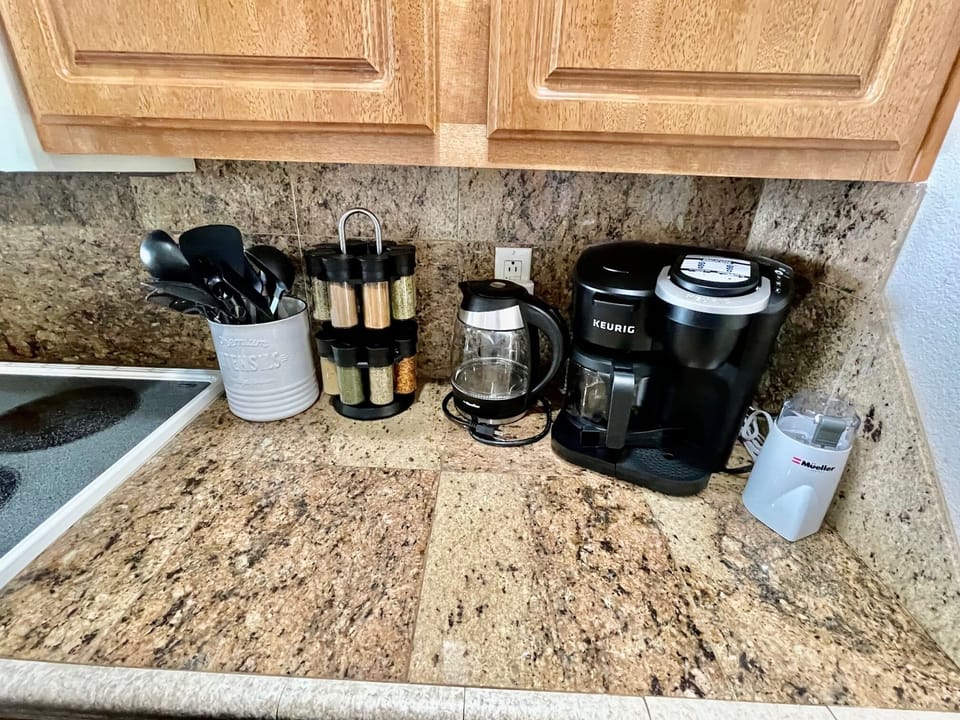 Keurig coffee maker, water kettle, coffee grinder, and spices.