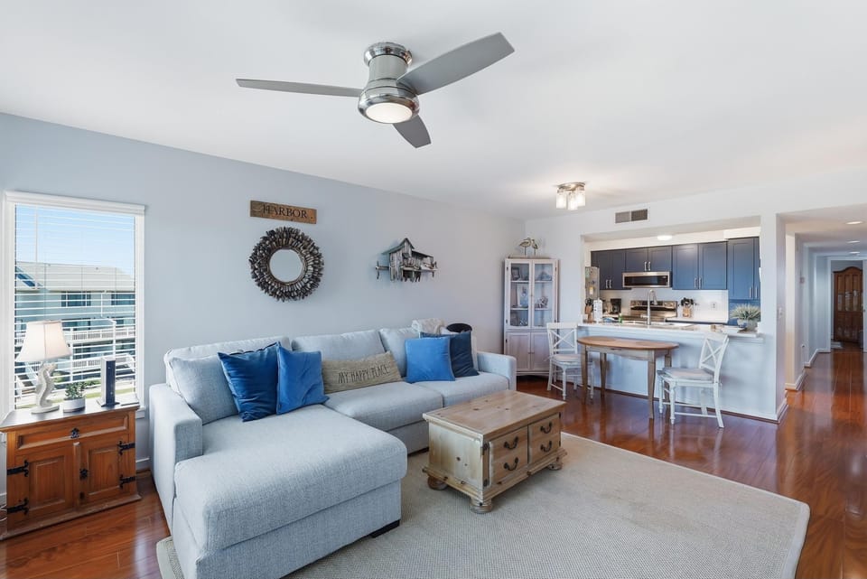 Living room with light gray sectional, rustic wooden coffee table, blue accent pillows, and hardwood floors.