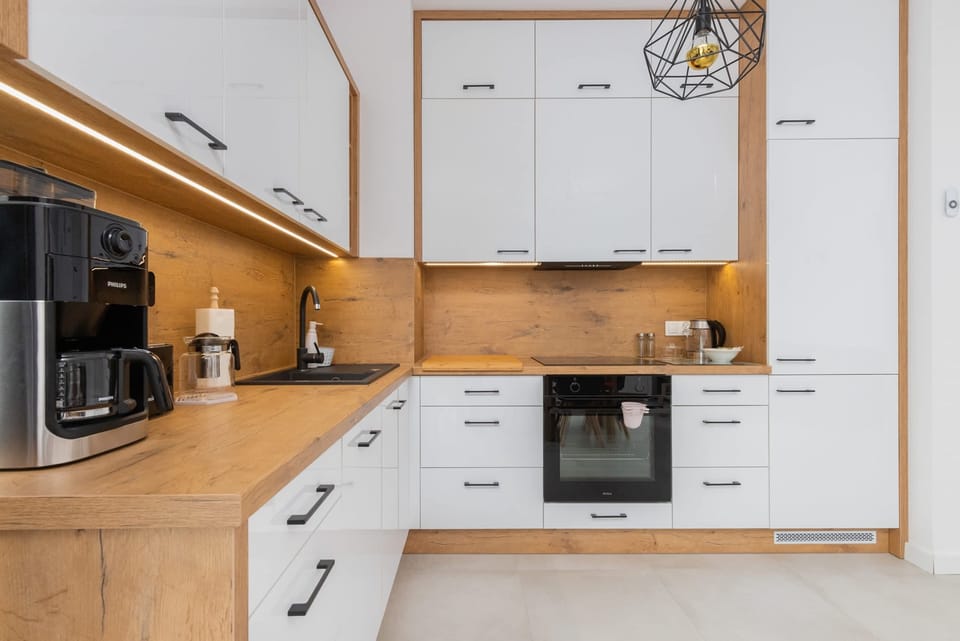 A contemporary kitchen with wooden cabinets, white drawers, and modern appliances such as an oven and stovetop.