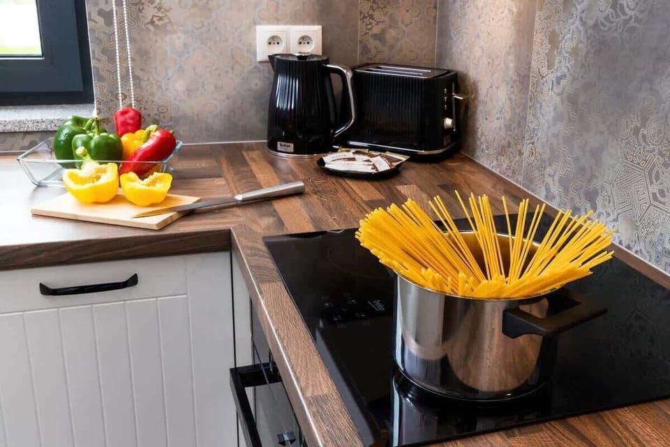 The counter showcases a pot of pasta, spices, and colorful ingredients, creating a cozy cooking atmosphere.