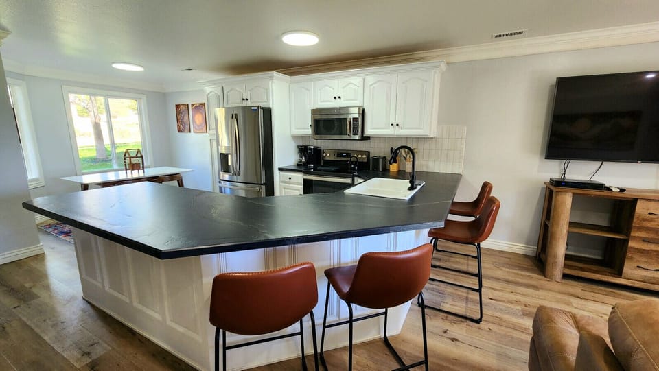 Spacious, modern kitchen with large island seating, stainless appliances, and bright dining area overlooking outdoors
