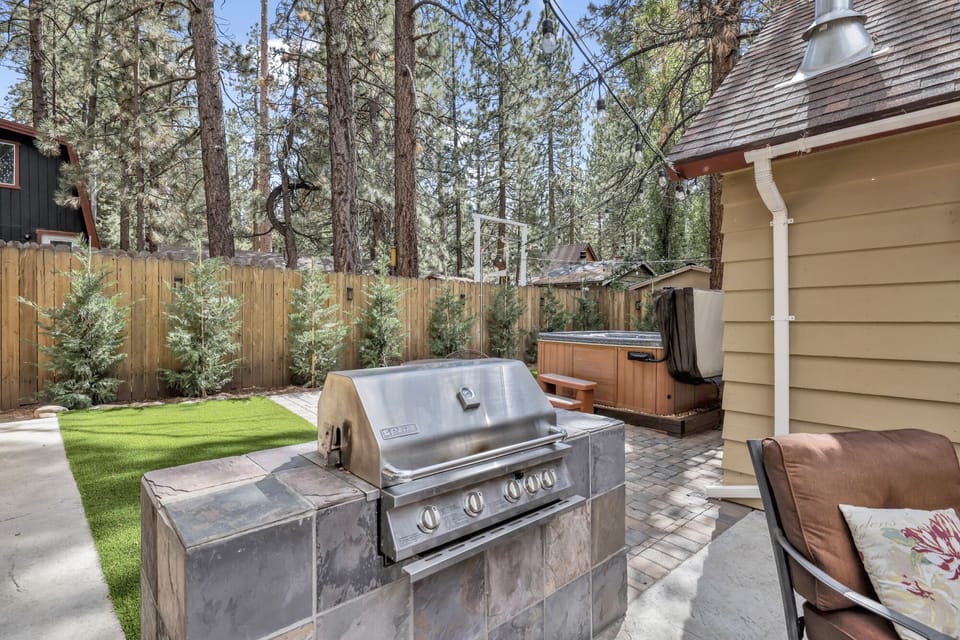 Private outdoor hot tub, with comfortable seating and a BBQ, surrounded by tall pines, perfect for relaxing under the trees after a day of adventure—enjoy peaceful forest views, fresh air, and a truly rejuvenating stay.