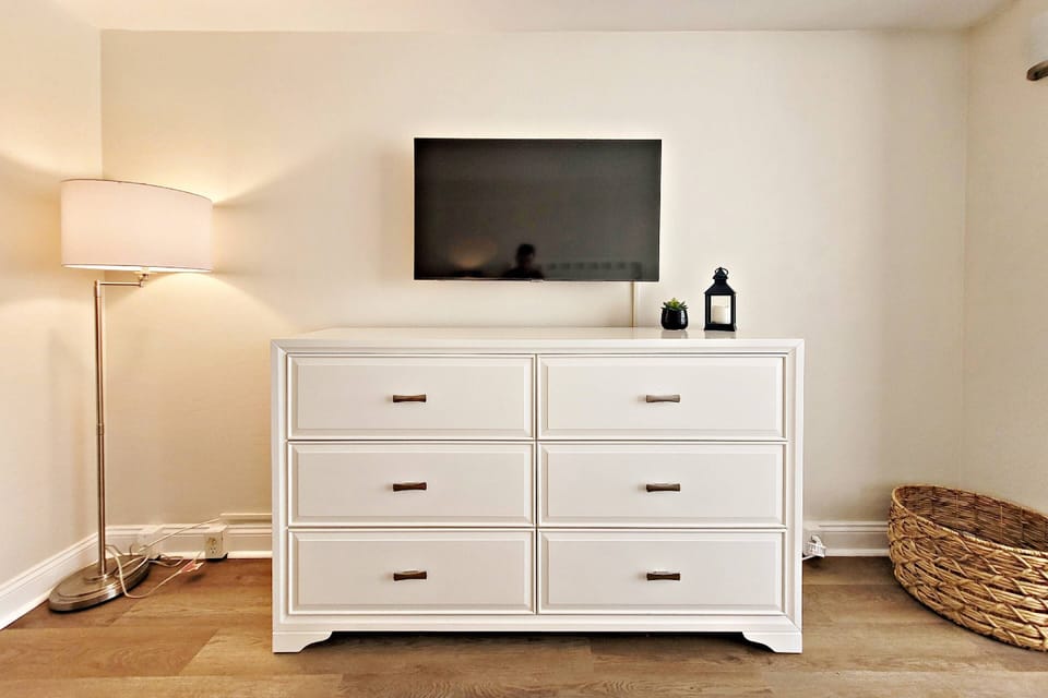 ..a long dresser with a 43" smart TV with cable and a floor lamp.