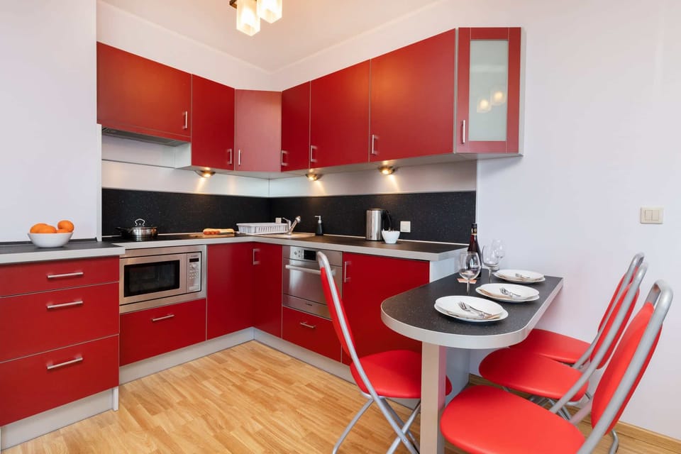 Fully equipped kitchen with red cabinetry, a bar-style counter, and modern appliances.
