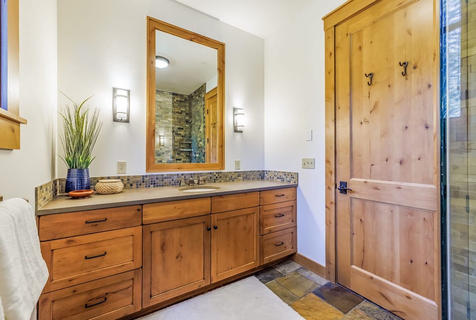 Main Floor : En-Suite Bathroom to Bedroom 1 with warm light, wood cabinetry + bronze accents.