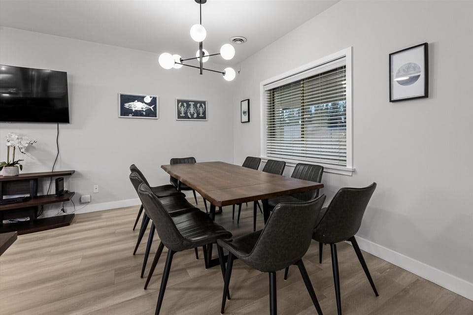 Spacious dining area with a large table that seats eight, perfect for family meals, group gatherings, or game nights. Modern lighting and stylish décor create a warm and inviting atmosphere.