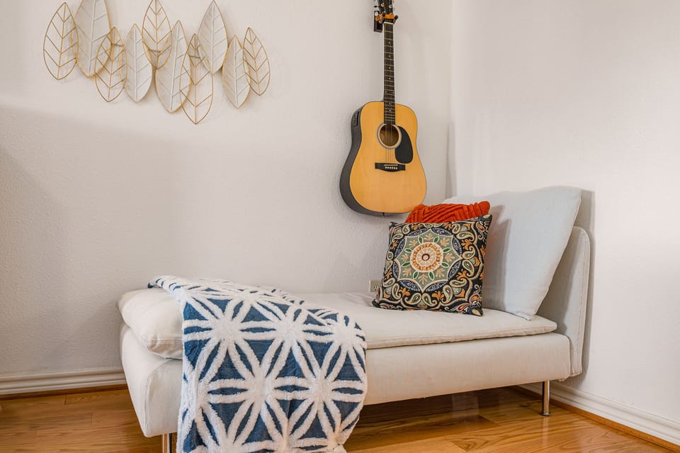 Cool sitting are with guitar in primary bedroom