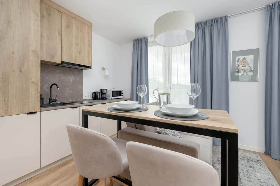 The living area features a sleek dining table and a flat-screen television.