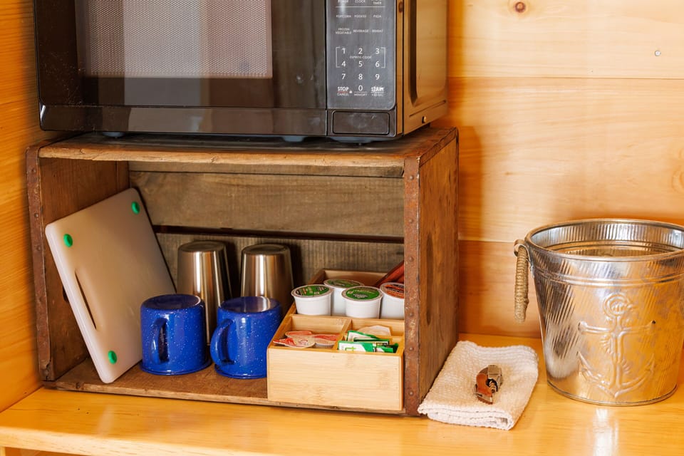 Keurig coffee maker, microwave, a mini fridge, utensils, mugs, cups, and K-Cups