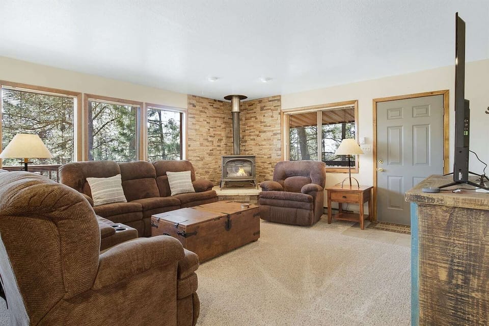 Living room with gas stove connected to thermostat. The couches have four recliners at each end and the couch chair is also a recliner.