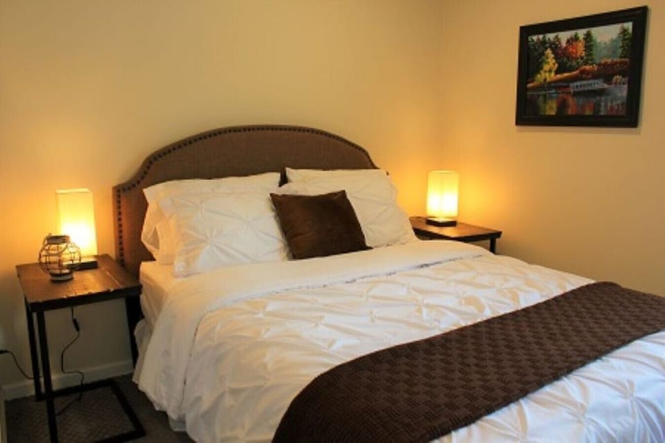 Indulge in ultimate comfort and relaxation in our short-term rental's bedroom featuring a queen-size bed. Drift off into a restful slumber in this tranquil haven, thoughtfully designed with your utmost comfort in mind. The plush bedding, soft lighting, an