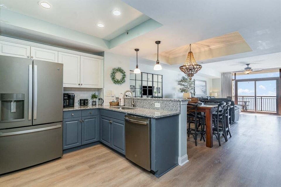 This wide view showcases the seamless flow between the modern kitchen, the formal dining area, and the spacious living room beyond.
