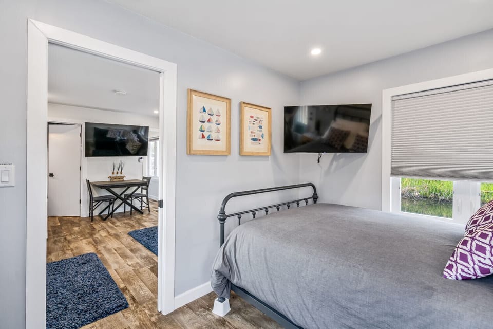 Cozy primary bedroom with comfortable queen bed and mounted TV