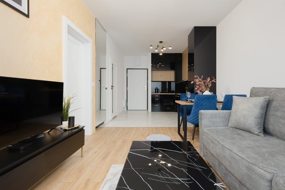 A cozy living space with a large gray sofa, a flat-screen TV, and a chic black-and-white rug, creating a stylish and functional area.

