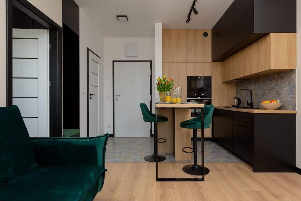 A compact kitchenette with wooden cabinets, a modern backsplash, and built-in appliances, ideal for efficient cooking.