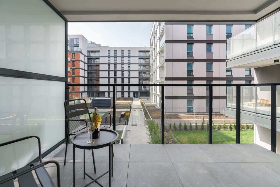 Another view of the balcony area, showing outdoor seating and a pleasant view of neighboring buildings.