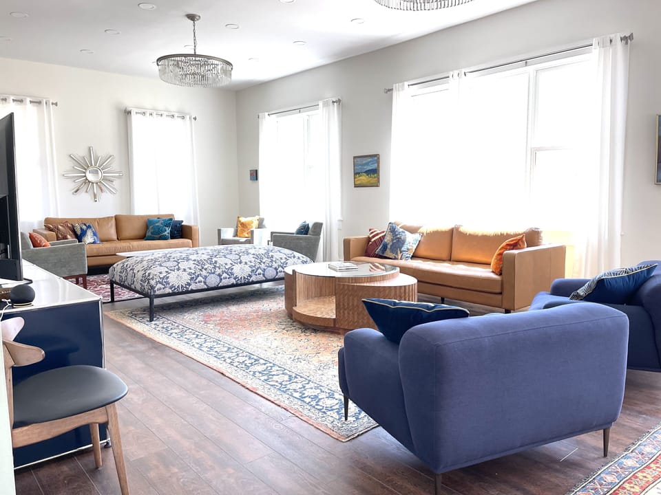 40’ living/dining room with 2 leather couches, 5 armchairs, 6’ ottoman and TV. 