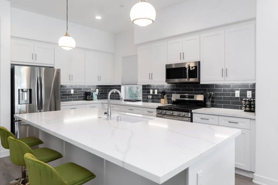 Bright kitchen w/ large island, bar seating & sleek stainless steel appliances