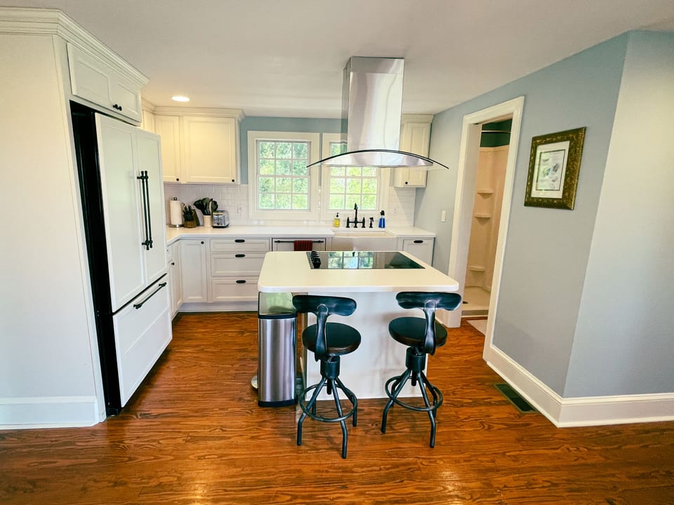 A beautiful modern kitchen with island oven, cooktop, and bar seating.