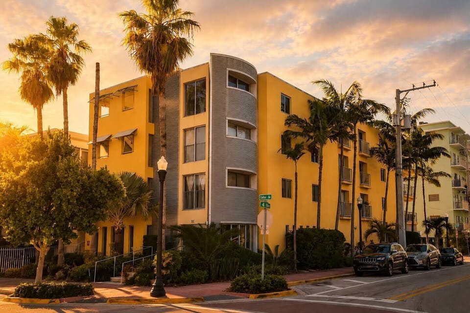 Golden hour light illuminates this vibrant Miami Beach building, where tall palm trees and lush greenery frame the sun-drenched architecture. Enjoy easy beach access and a walkable location near the city skyline and local bike rentals.
