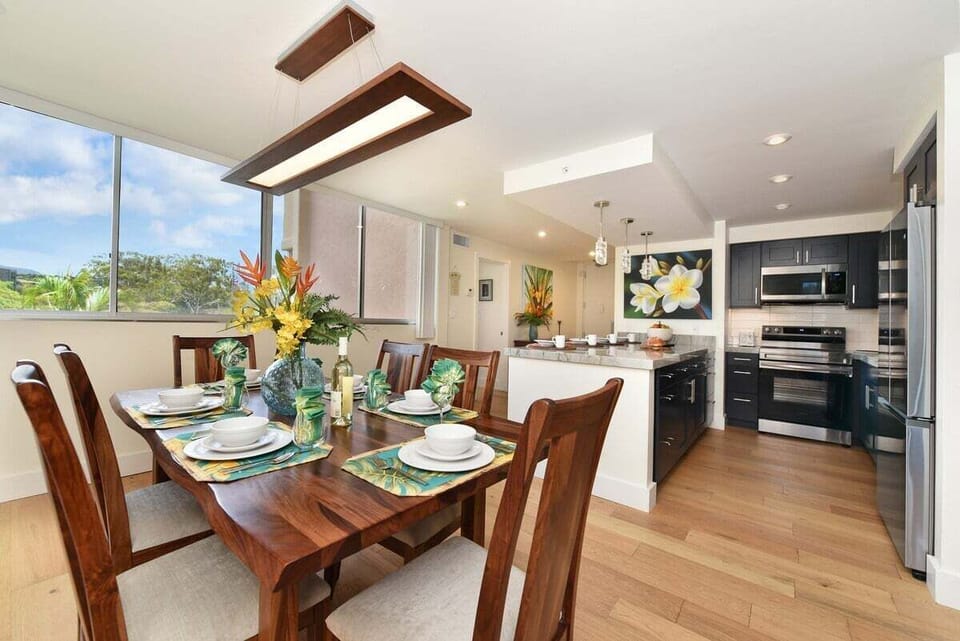 Dining table set for a feast, complete with floral centerpiece and a kitchen ready for island flavors.