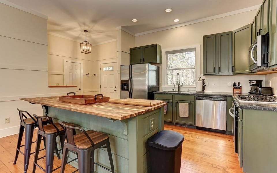 Elegant green cabin kitchen with modern lighting.