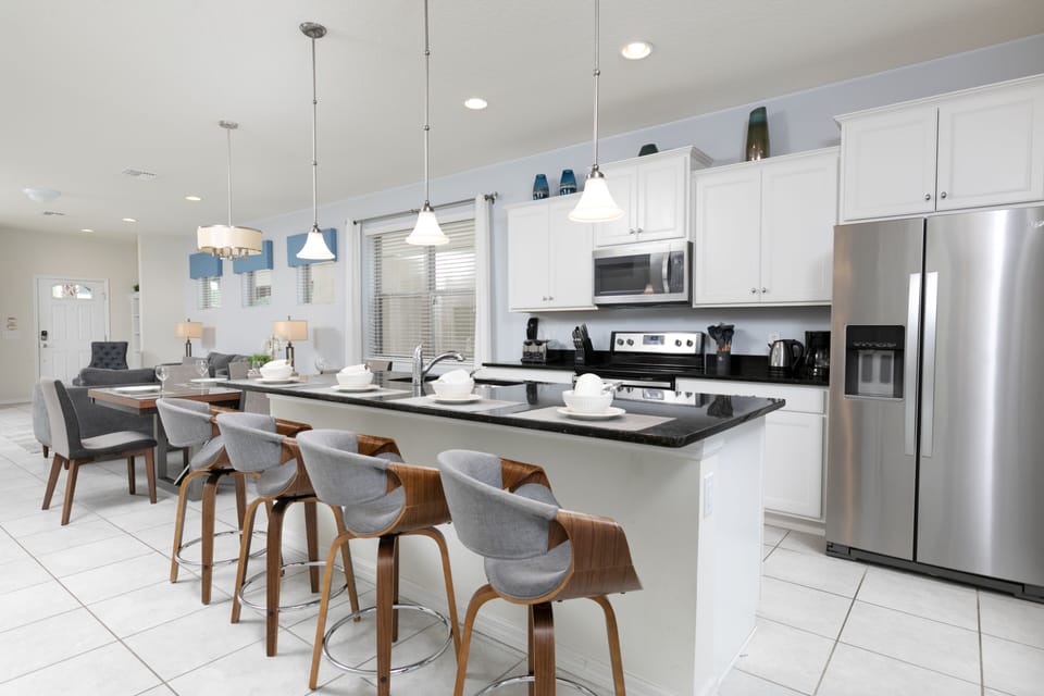 Spacious kitchen features an island with a sink and 4 bar stools