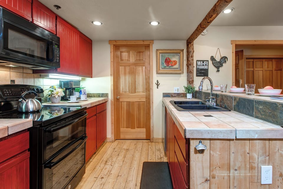 Fully Equipped Kitchen with tiled countertops, double oven, full bath access and bare seating for 3