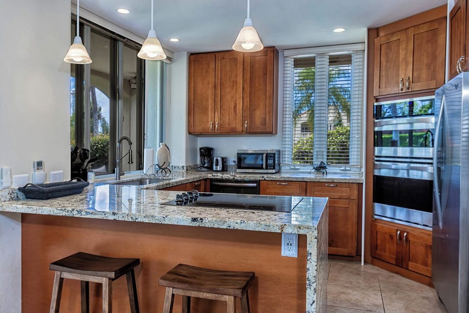 Your fully equipped gourmet kitchen features gleaming granite countertops, modern stainless appliances, and a handy breakfast bar—perfect for crafting morning coffee or preparing island-inspired feasts.
