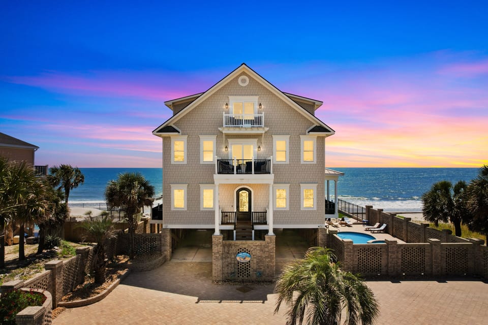Stunning beachfront home with private pool and direct ocean access under breathtaking sunset skies.