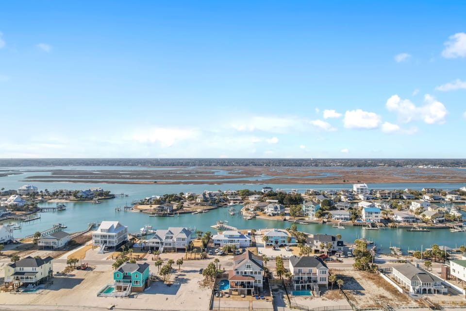 Stunning aerial view reveals a picturesque waterfront community with colorful beach houses nestled along pristine canals and coastline.