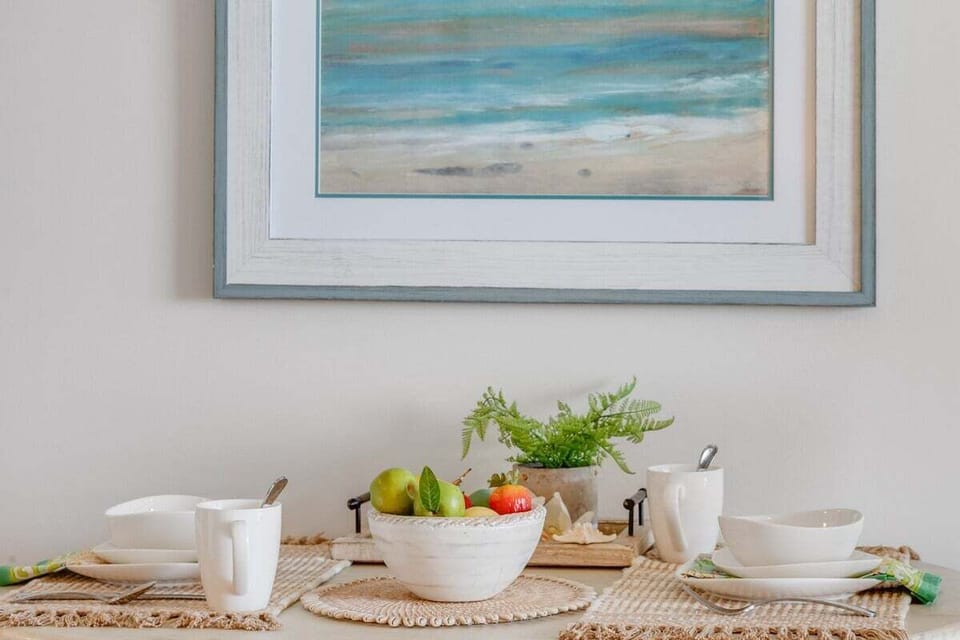 A charming dining space with a wooden table, beach-inspired artwork, and natural accents