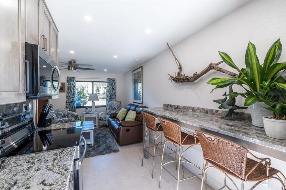 Modern kitchen and living area with granite countertops and natural light