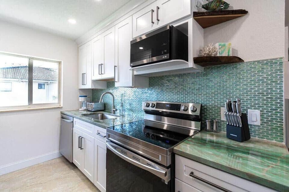 Modern kitchen with green tile backsplash and stainless steel appliances