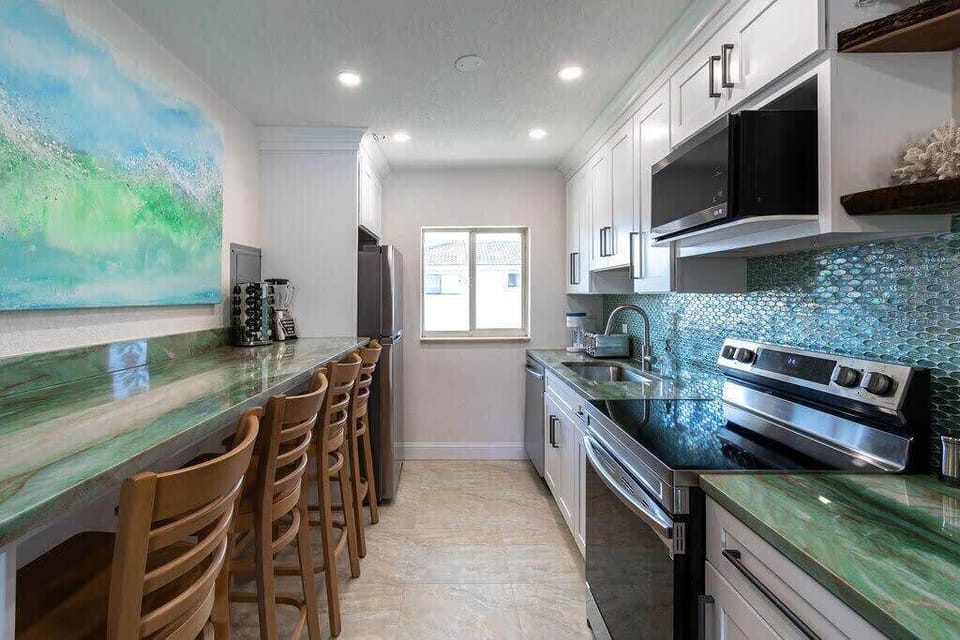Modern kitchen with green marble countertops and a mosaic tile backsplash