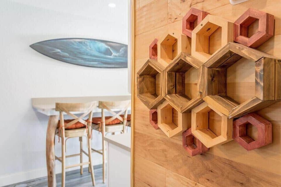 Rustic hexagonal wooden wall art adds character to the dining area with surfboard decor in the background.