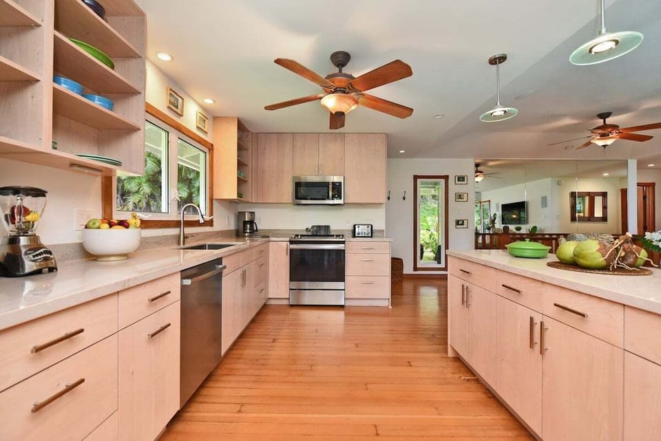 Elegant kitchen with wooden flooring, ceiling fans, and a functional open layout.