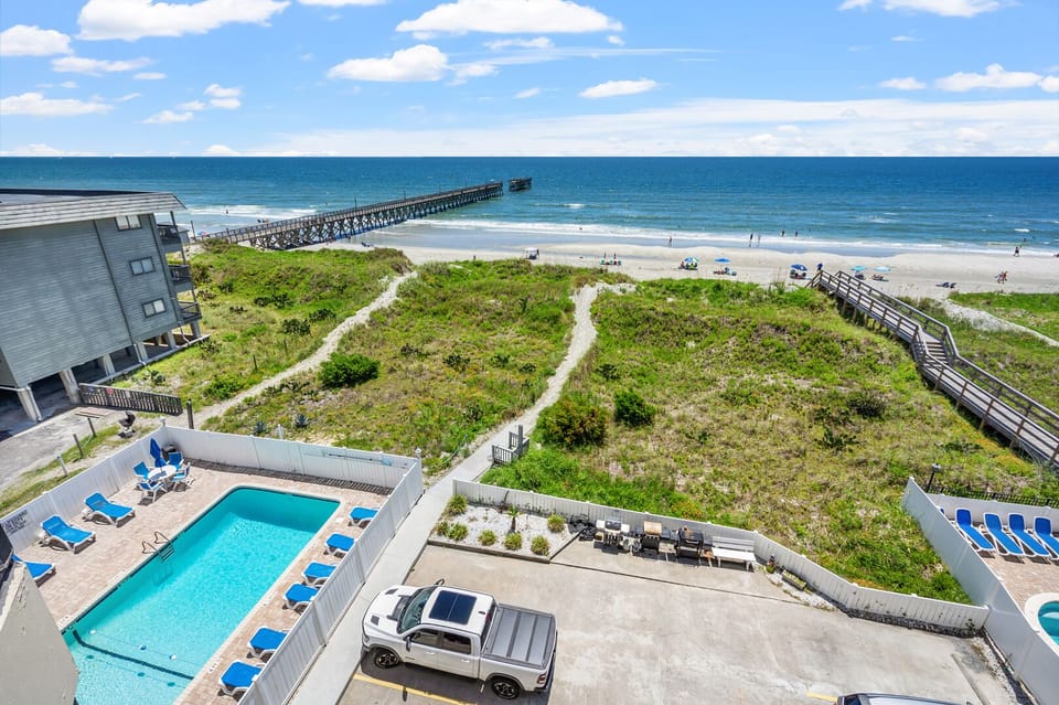 Pool and boardwalk with the pier beyond at Sedgefield 403, a 3-bedroom vacation rental in North Myrtle Beach