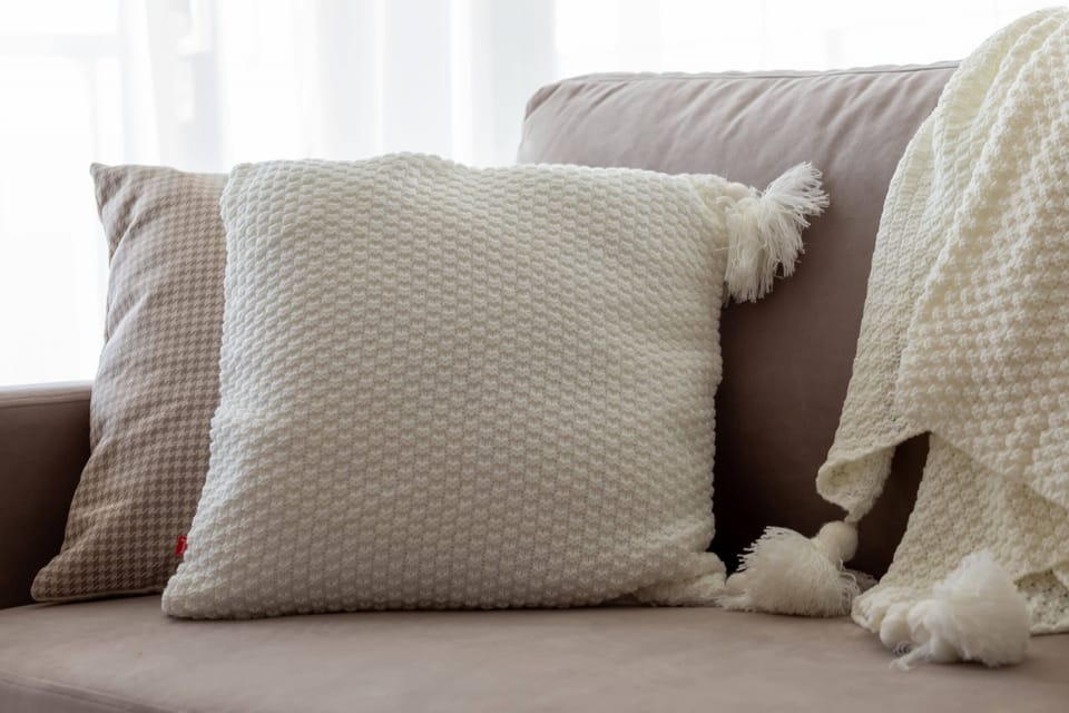 Close-up of the soft cushions and blanket lying on the sofa.