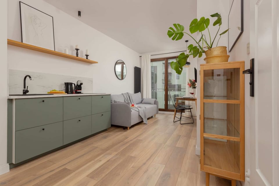 A kitchen with green cabinets, a modern stove, and open wooden shelves for a clean and stylish look.