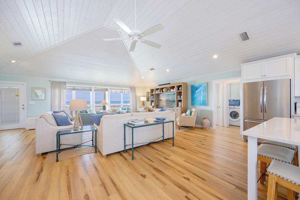 Sunlight filters through windows as you relax on the sofa queen in the living room with coastal views