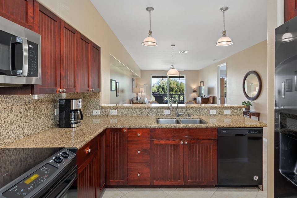 - Kitchen with granite countertops, rich wood cabinets, and modern appliances   - Double sink faces an open view to the living area for easy conversation   - Pendant lighting adds style while keeping the workspace bright