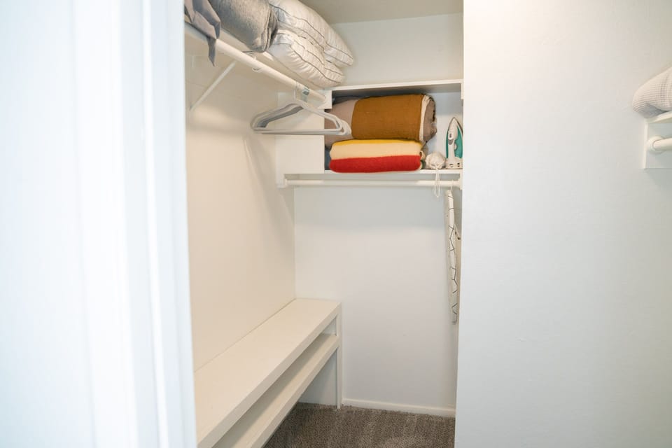 Extra blankets, pillows, an iron and a steamer in the primary bedroom's walk-in closet
