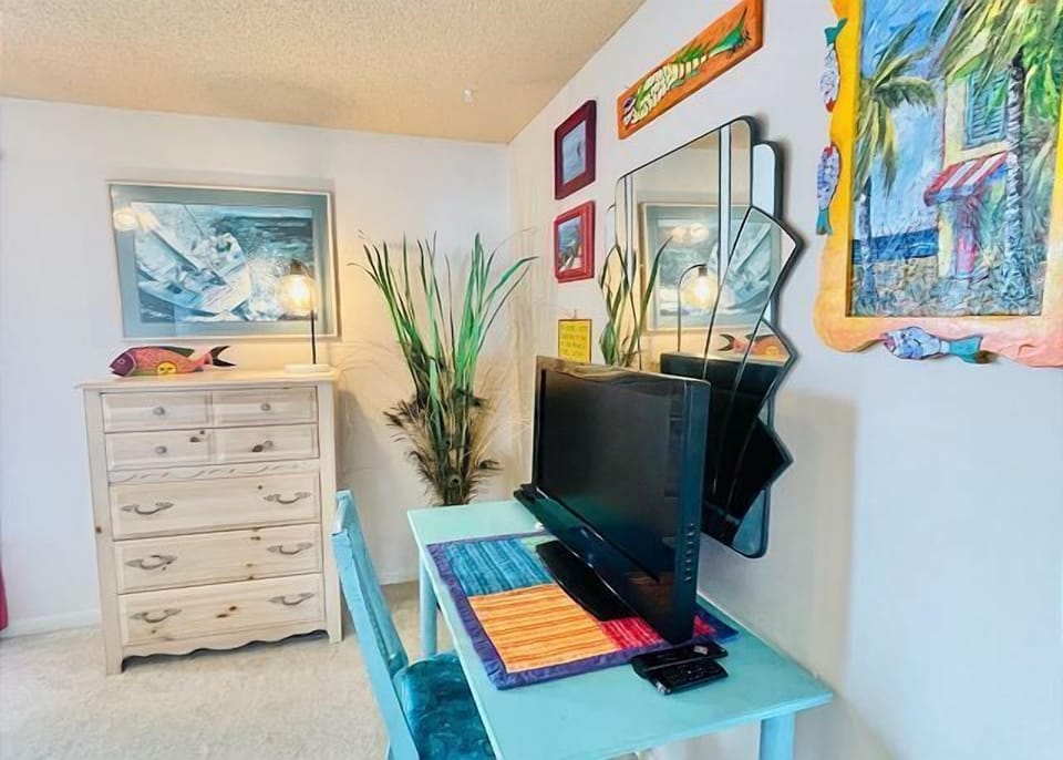 Your bright bedroom workspace features cheerful tropical artwork, a convenient desk for remote work, and coastal-inspired furnishings that make you feel right at home.