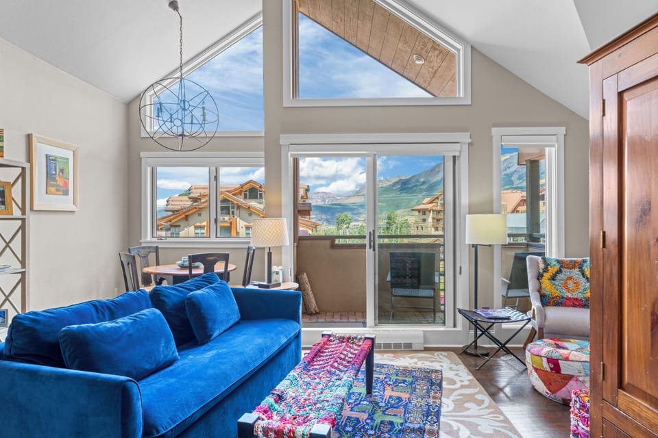 A vibrant blue velvet couch adds a pop of color to this cozy living room with a stunning mountain view. (40A)